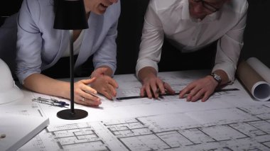 Mimarlar birlikte çalışır, bina planlarını ve planlarını analiz eder, bir ofiste tasarım kavramlarını ve mühendislik unsurlarını tartışırlar..