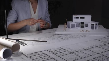 Mimarlar, masanın üzerinde modern ev ölçeğinde bir modelle inşaat planları ve mimari çizimler üzerinde çalışıyorlar, tasarım planlıyorlar. İş ve mimarlık kavramı