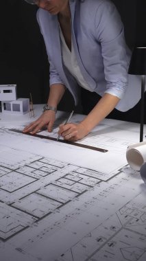 Mimari planlar ve ölçekli modeller üzerinde çalışan kadın mimar, inşaat planlama ve mühendisliğe odaklanıyor. Gösterişsiz ışıklandırmada mimari ve iş konsepti