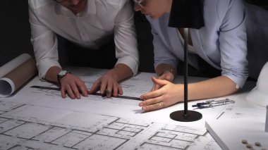 Mimarlar birlikte çalışır, bina planlarını ve planlarını analiz eder, bir ofiste tasarım kavramlarını ve mühendislik unsurlarını tartışırlar..