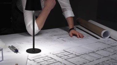 Çok çalışan mimar gece yarısı çalışırken baş ağrısı ve stres hissederek inşaat planları ve tasarım yapmayı planlıyor..