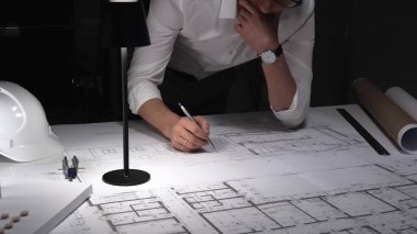 Çok çalışan mimar gece yarısı çalışırken baş ağrısı ve stres hissederek inşaat planları ve tasarım yapmayı planlıyor..