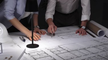 Profesyonel mimarlar ve mühendisler bina planlarını, inşaat planlarını ve mimari tasarım detaylarını gece geç saatlerde analiz etmeyi tartışıyorlar. İş ve mimarlık kavramı