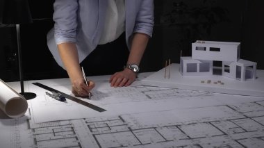 Mimarlar, masanın üzerinde modern ev ölçeğinde bir modelle inşaat planları ve mimari çizimler üzerinde çalışıyorlar, tasarım planlıyorlar. İş ve mimarlık kavramı