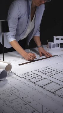 Mimari planlar ve ölçekli modeller üzerinde çalışan kadın mimar, inşaat planlama ve mühendisliğe odaklanıyor. Gösterişsiz ışıklandırmada mimari ve iş konsepti