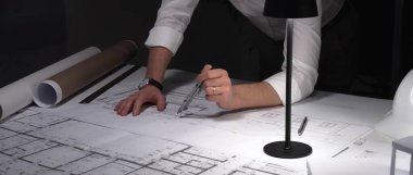 Mimarın dikkatle planladığı planlar bir masada, odaklanmış bir ortamda yapısal mühendislik projeleri tasarlıyor..