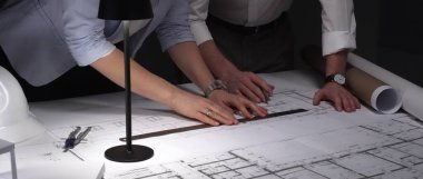 Profesyonel mimarlar ve mühendisler bina planlarını, inşaat planlarını ve mimari tasarım detaylarını gece geç saatlerde analiz etmeyi tartışıyorlar. İş ve mimarlık kavramı