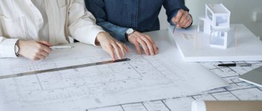 Yenilikçi bir bina projesinde işbirliği yapan mimarlar, modern bir ev modeli tasarlarken aynı zamanda planları analiz eden ve profesyonel bir ofiste mimari tasarım araçları kullanan mimarlar.