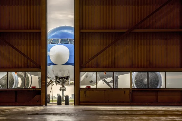 Самолет перед полуоткрытой дверью ангара — стоковое фото