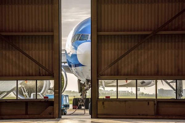Самолет перед полуоткрытой дверью ангара — стоковое фото