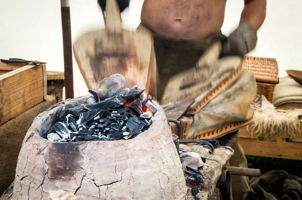 Traditional blacksmith uses bellows to keep a fire — Stock Photo, Image