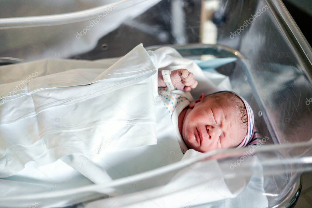 Newborn baby boy in a small hospital bed two hours after birth