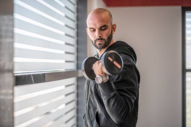 Spor salonunda ağırlık çalışan bir adamın portresi.