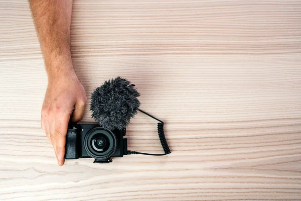 Muž Držící Ruku Malé Profesionální Černošky Fotoaparát Mikrofonem Dřevěném Stole — Stock fotografie