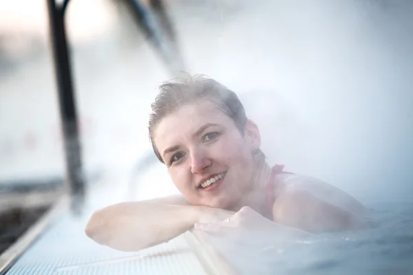 Mujer joven relajándose en la piscina termal . — Foto de Stock