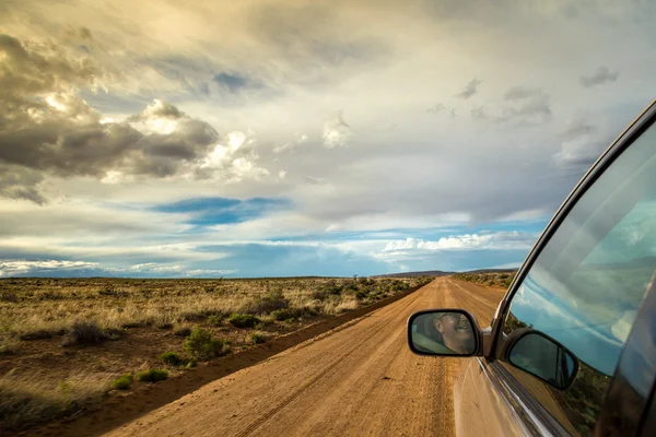 Uomo sorridente guida attraverso la natura selvaggia sulla strada sterrata — Foto Stock