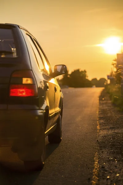 Bilen går mot solnedgången genom landsbygden — Stockfoto