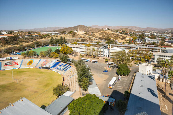 The Windhoek High School Stadium in Namibia -18 August, 2025: is a sports venue with a rugby field, hockey turf, and colorful stands, set against Windhoeks scenic hills 
