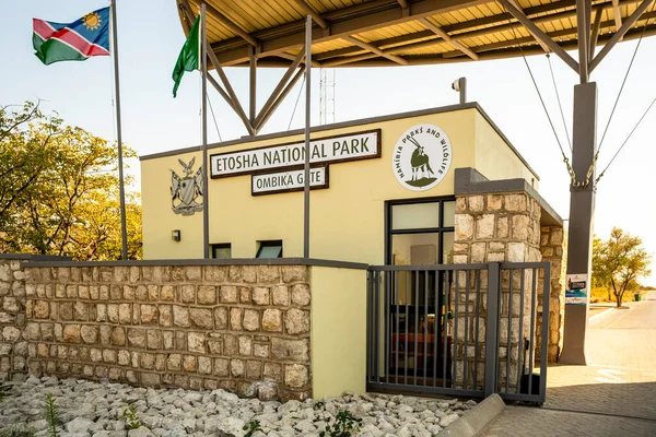 Okaukuejo Kamp Girişi, Etosha Milli Parkı, Namibya - 19 Ağustos 2025: Taş kapıya ve akşam ışığı olan kuleye giden asfalt yol.