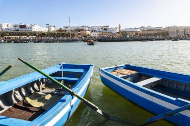 Rabat, Fas Bou Regreg Nehri manzaralı renkli balıkçı tekneleri nazikçe suda yüzüyor ve arka planda tarihi Hasan Kulesi yükseliyor. Açık ve güneşli bir günde yakalanan bu resim geleneğin karışımını sergiliyor. 