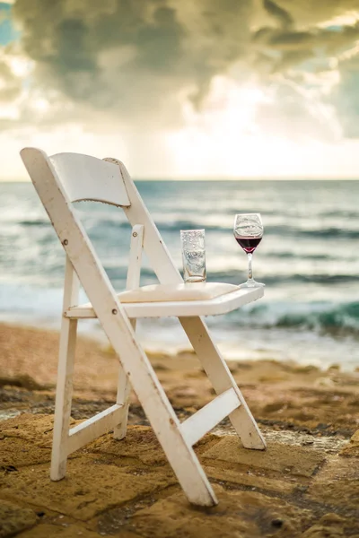 Vit stol med vinglas på en strand — Stockfoto