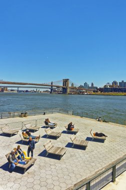 Aşağı Manhattan'daki Pier'de şezlonglarda dinlenen turistler