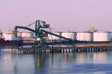 Gün batımında Ventspils Marina'da vinç ve petrol sığınakları