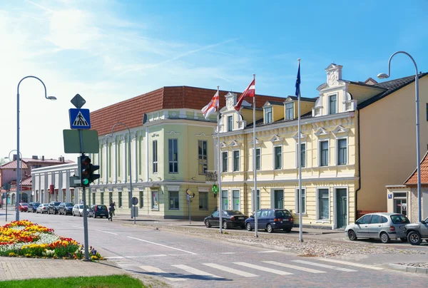Stará žlutá budova s vlajkami v Ventspils — Stock fotografie