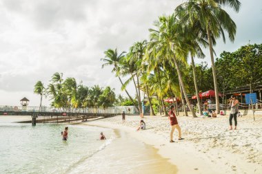 Couple take photos on Siloso Beach at Sentosa island resort clipart