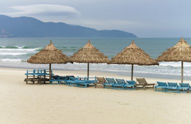 Çin Plajı'nda palmiye barınakları ve şezlonglar
