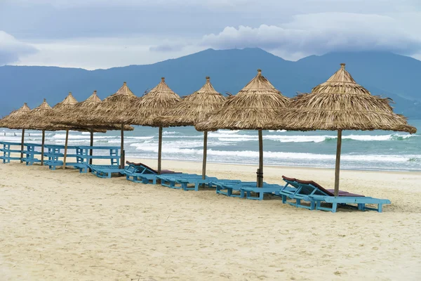 Refugios de palma y tumbonas en la playa de China — Foto de Stock