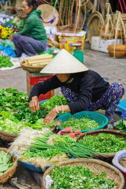 Asyalı tüccar sokak pazarında taze yeşillik satan