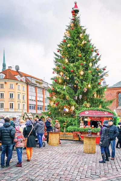 Mensen lopen rond kerstmarkt op het plein van de kathedraal van Riga — Stockfoto