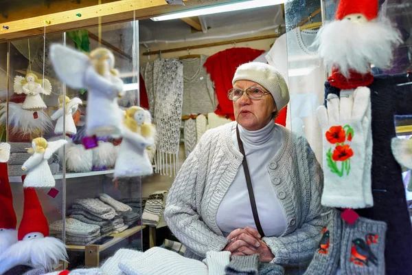 Žena prodávající slavnostní teplé oblečení na vánočním trhu v Rize — Stock fotografie