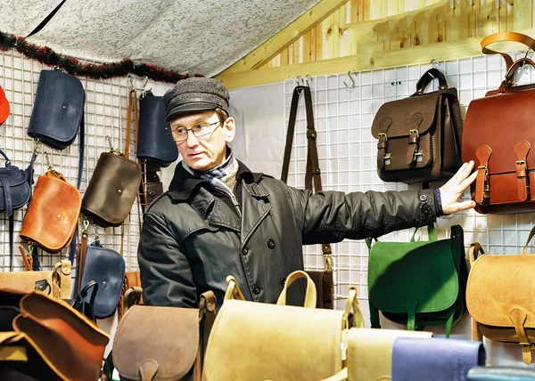 Hombre vendiendo bolsos de cuero hechos a mano en el mercado navideño de Vilna — Foto de Stock