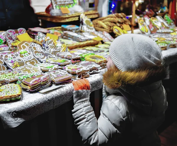 Criança em bolos de gengibre coloridos no mercado de Natal de Riga — Fotografia de Stock