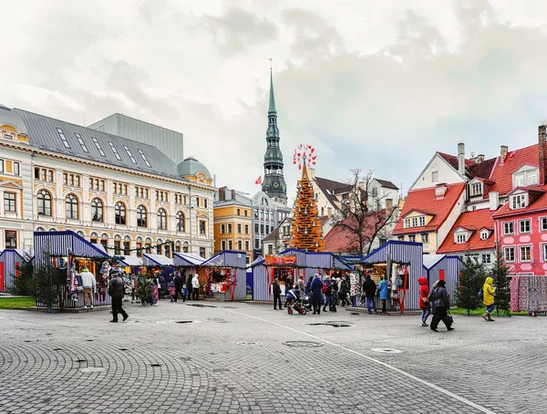 Pessoas no mercado de Natal de Riga com o campanário da Igreja de São Pedro — Fotografia de Stock