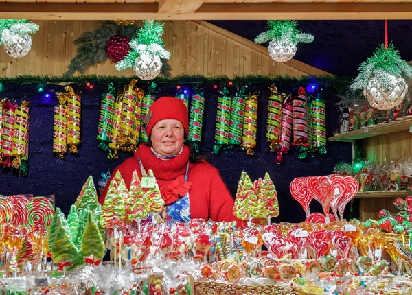 Verkäufer an Stand mit bunten Bonbons auf Vilnius Weihnachtsmarkt — Stockfoto