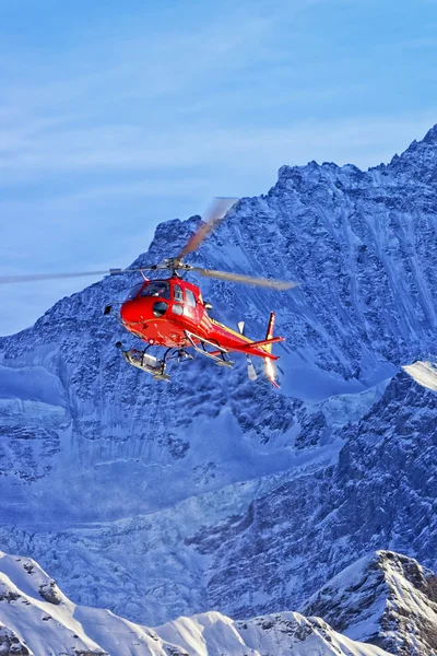 红色的直升机在瑞士的阿尔卑斯山，在冬日的阳光 — 图库照片
