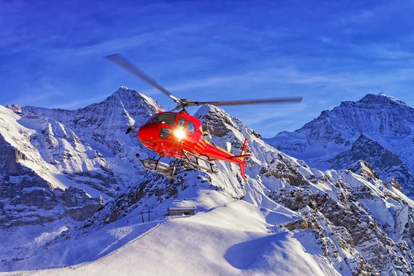 红色的直升机降落在瑞士滑雪胜地附近少女峰白雪皑皑 — 图库照片