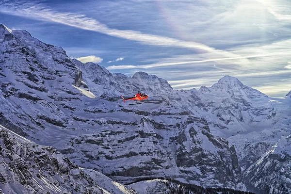 Röd helikopter på schweiziska Alperna flyger högt — Stockfoto