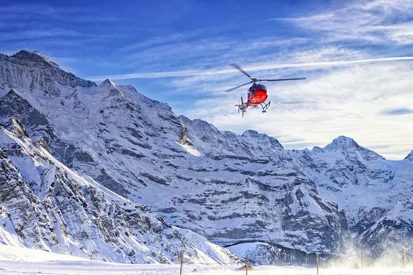 Elicottero rosso che vola sulle Alpi svizzere vicino alla montagna di Jungfrau — Foto Stock