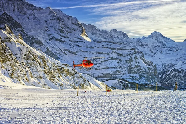 Elicottero rosso che vola vicino alla stazione sciistica svizzera vicino al monte Jungfrau — Foto Stock