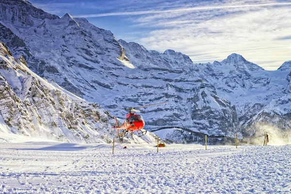 Красный вертолет взлетает на швейцарском горнолыжном курорте возле горы Юнгфрау — стоковое фото