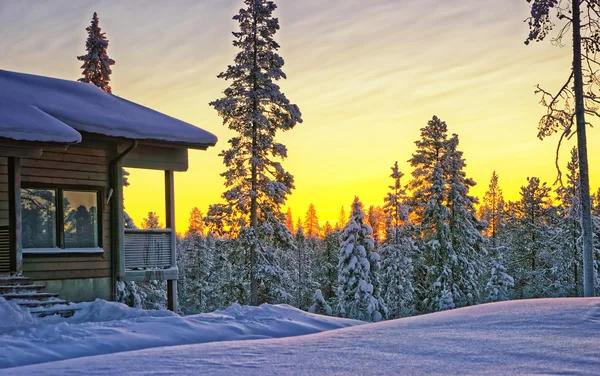 Houten huisje huis bij zonsondergang in de winter — Stockfoto