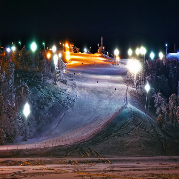 Snowboarders on the illuminated moumtain slope