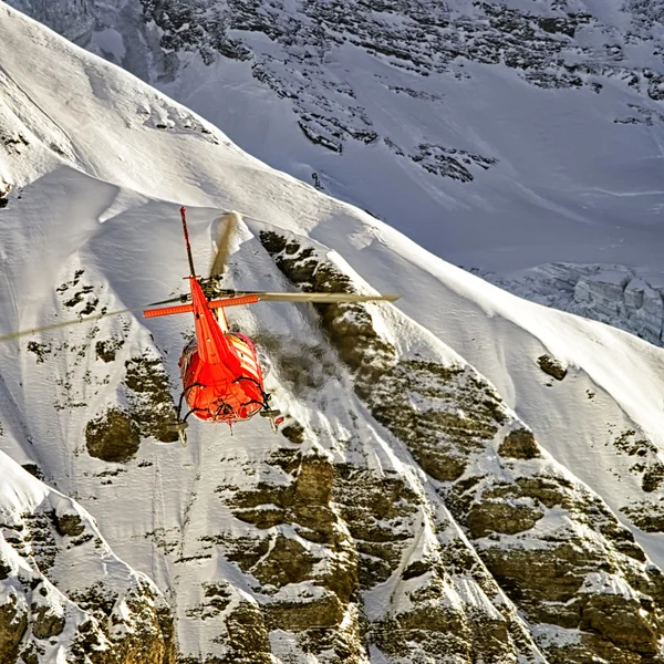 冬のアルプスで飛行中の赤いヘリコプター — ストック写真