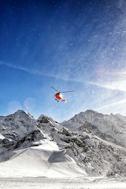 Kırmızı helikopter uçuş kar tozu ile kış Alpleri'nde