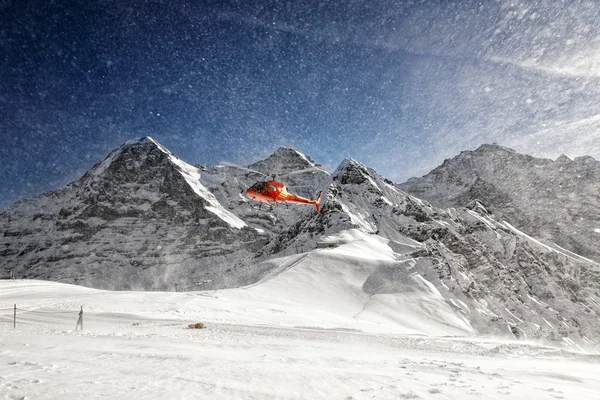 Decollo elicottero rosso con nuvole di neve in polvere di re alpino — Foto Stock