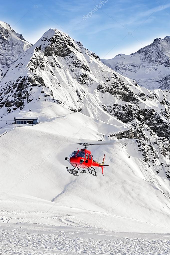 Red helicopter landing at swiss ski resort near Tschuggen peak